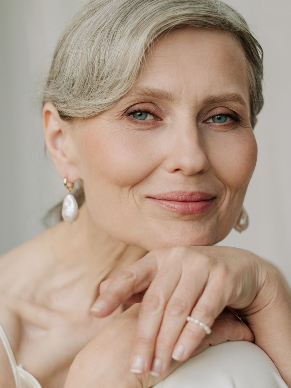 Elegant woman with grey hair and pearl earrings.