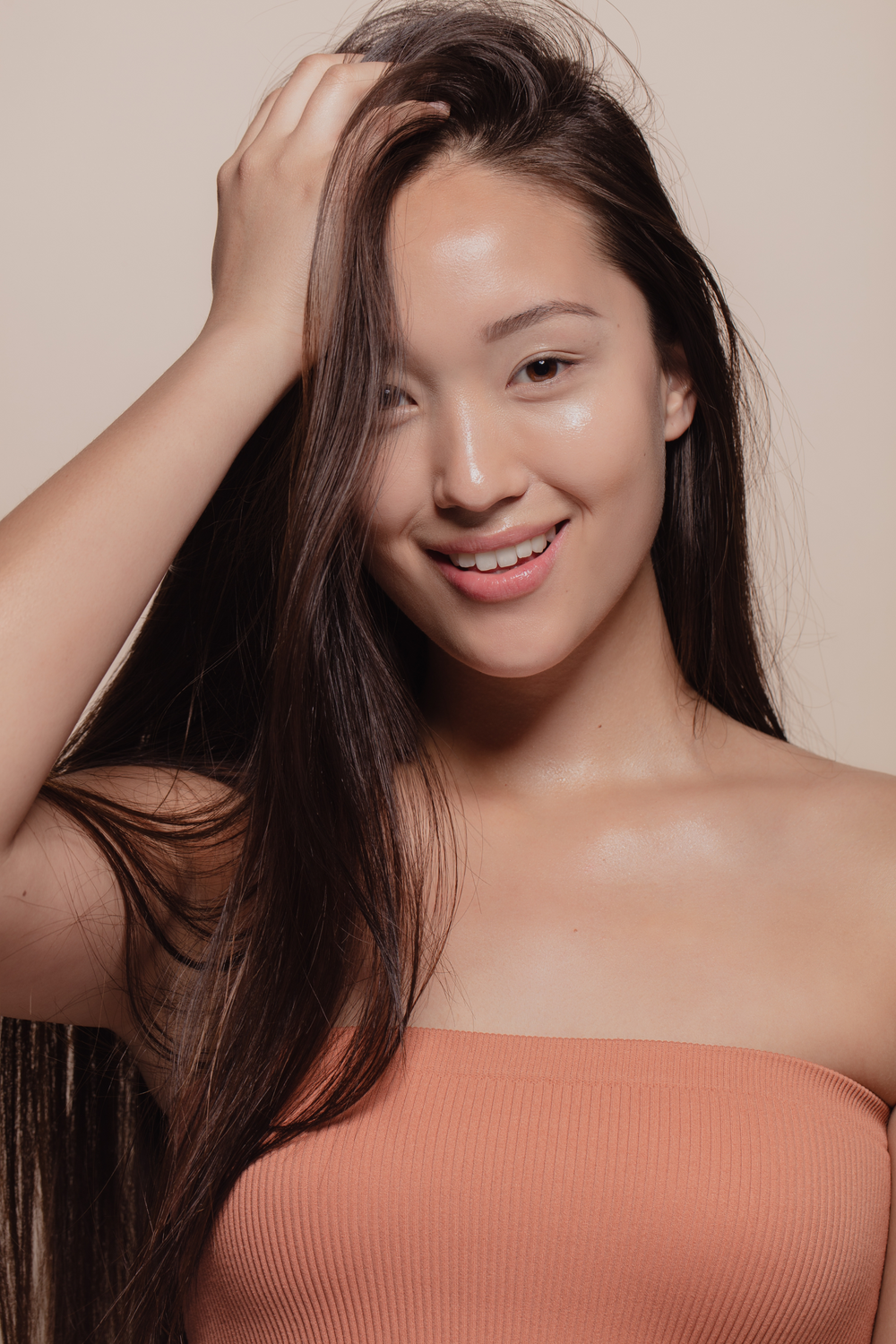 Smiling person with long hair and natural makeup.