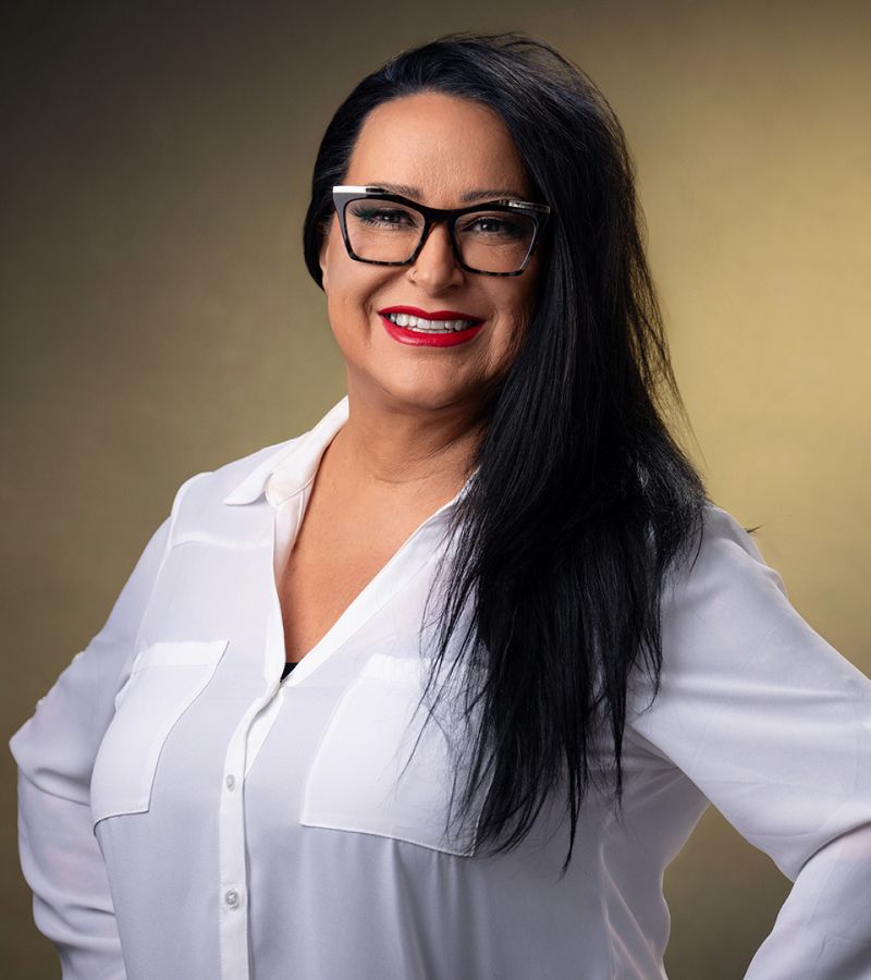 Woman with long hair and glasses smiling.
