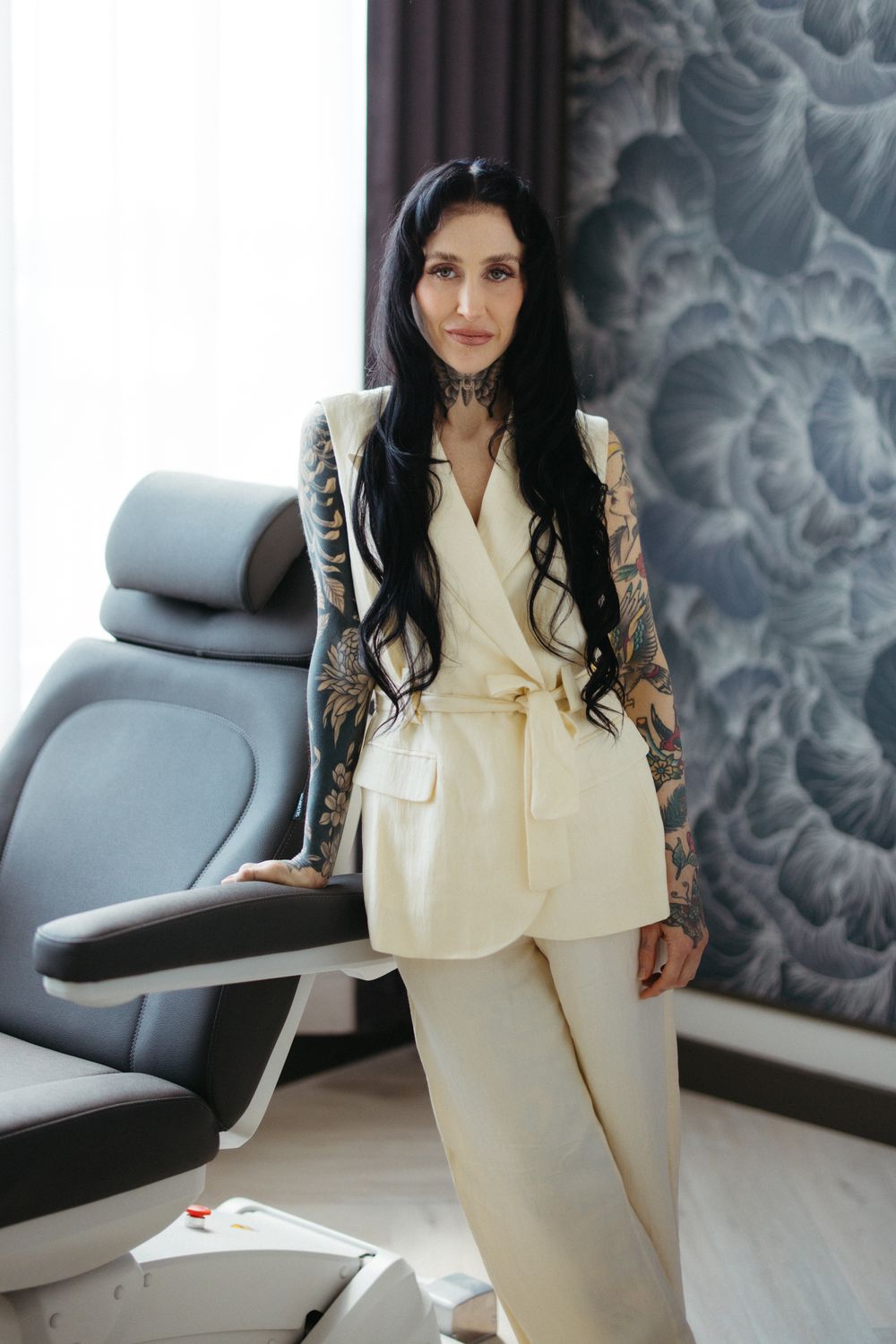 Woman with neck tattoo smiling in green shirt.