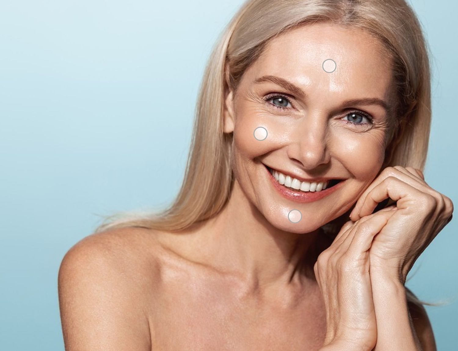Smiling woman with clear skin against blue background.