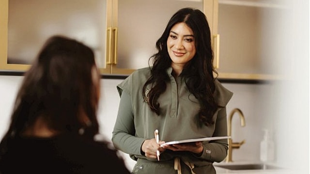 Woman smiling while taking notes in conversation.