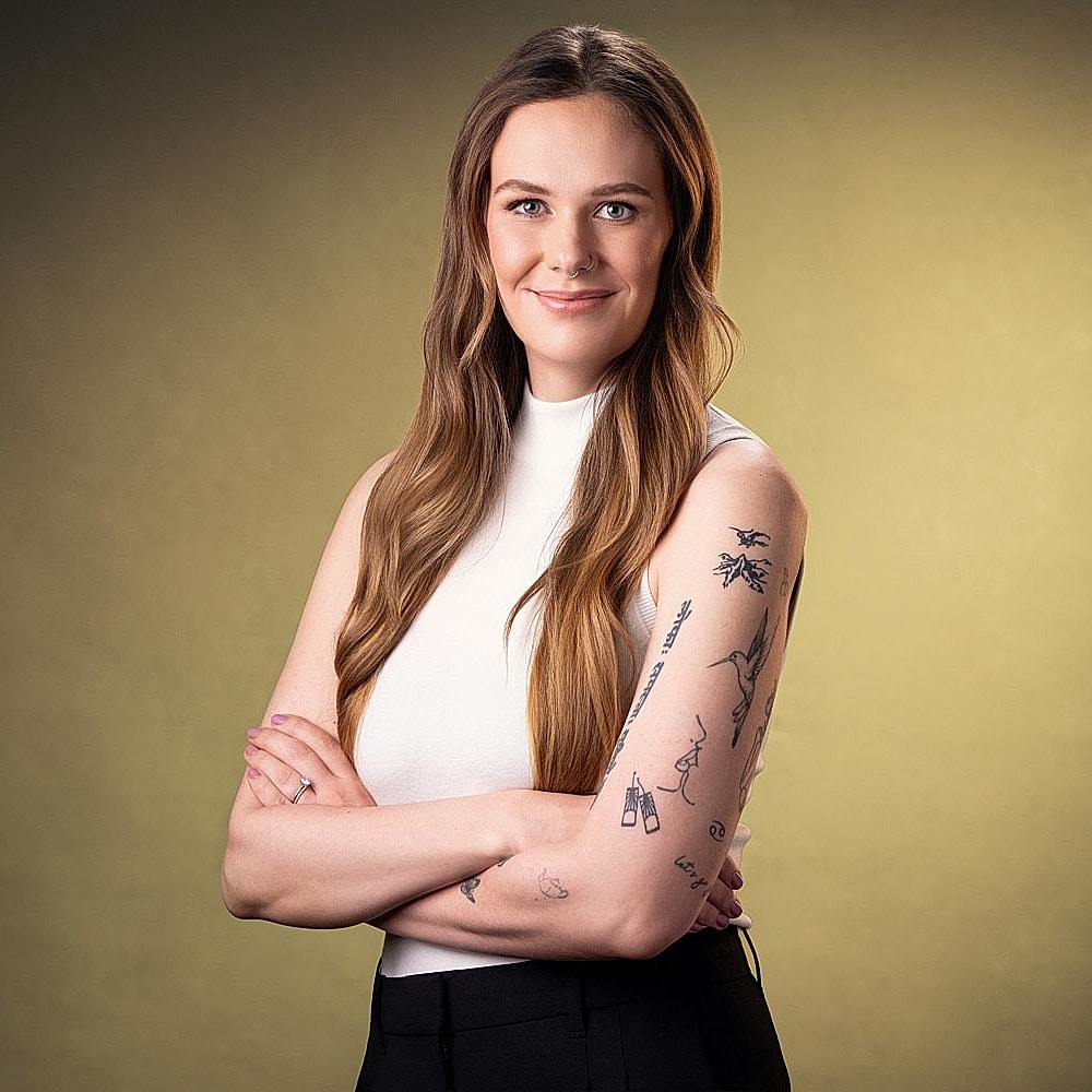 Smiling woman with long hair and tattoos.