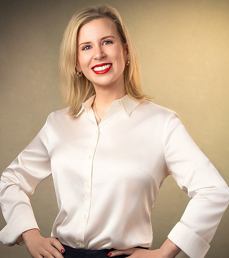 Woman with long hair and glasses smiling.