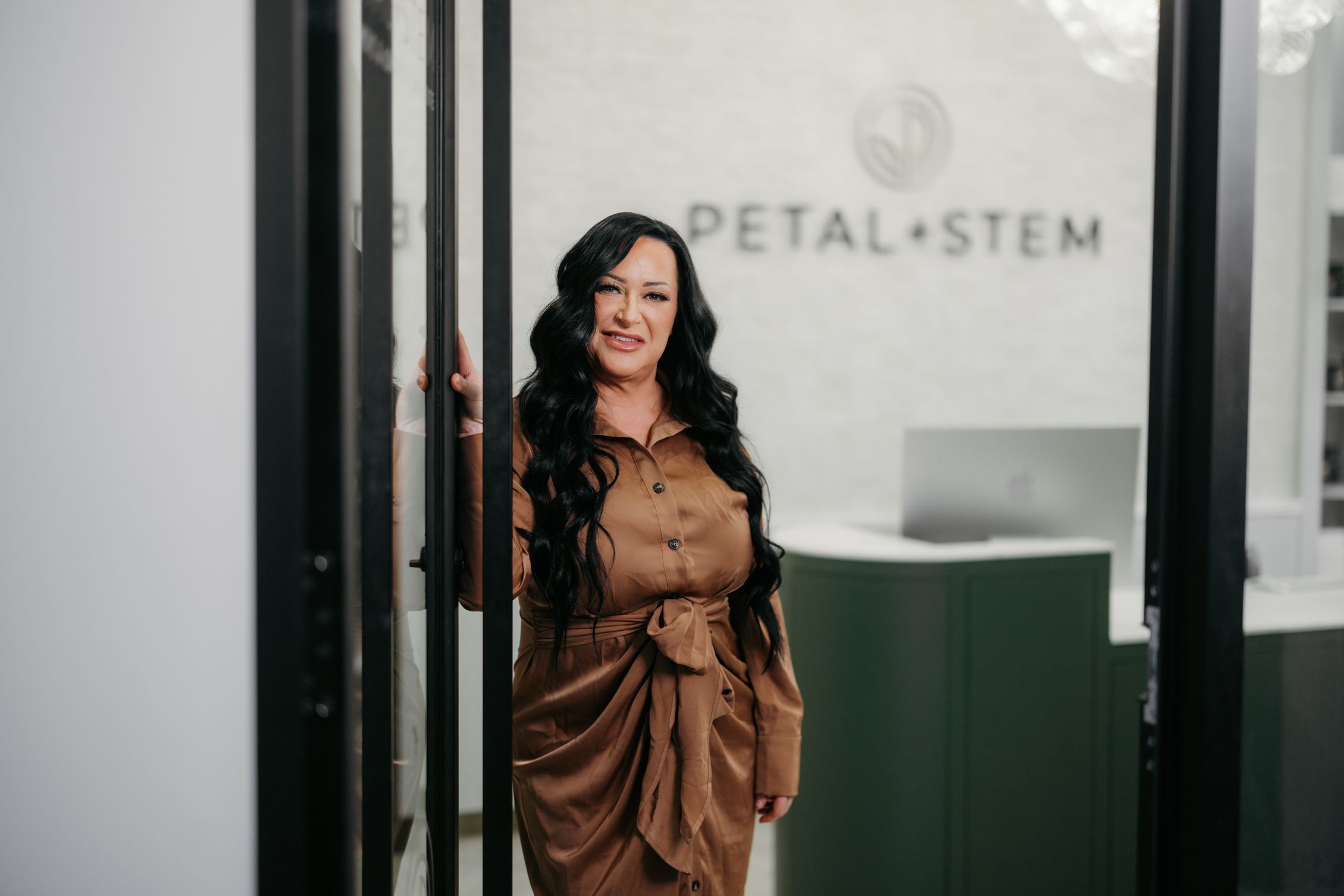 Smiling woman in white suit against gradient background.