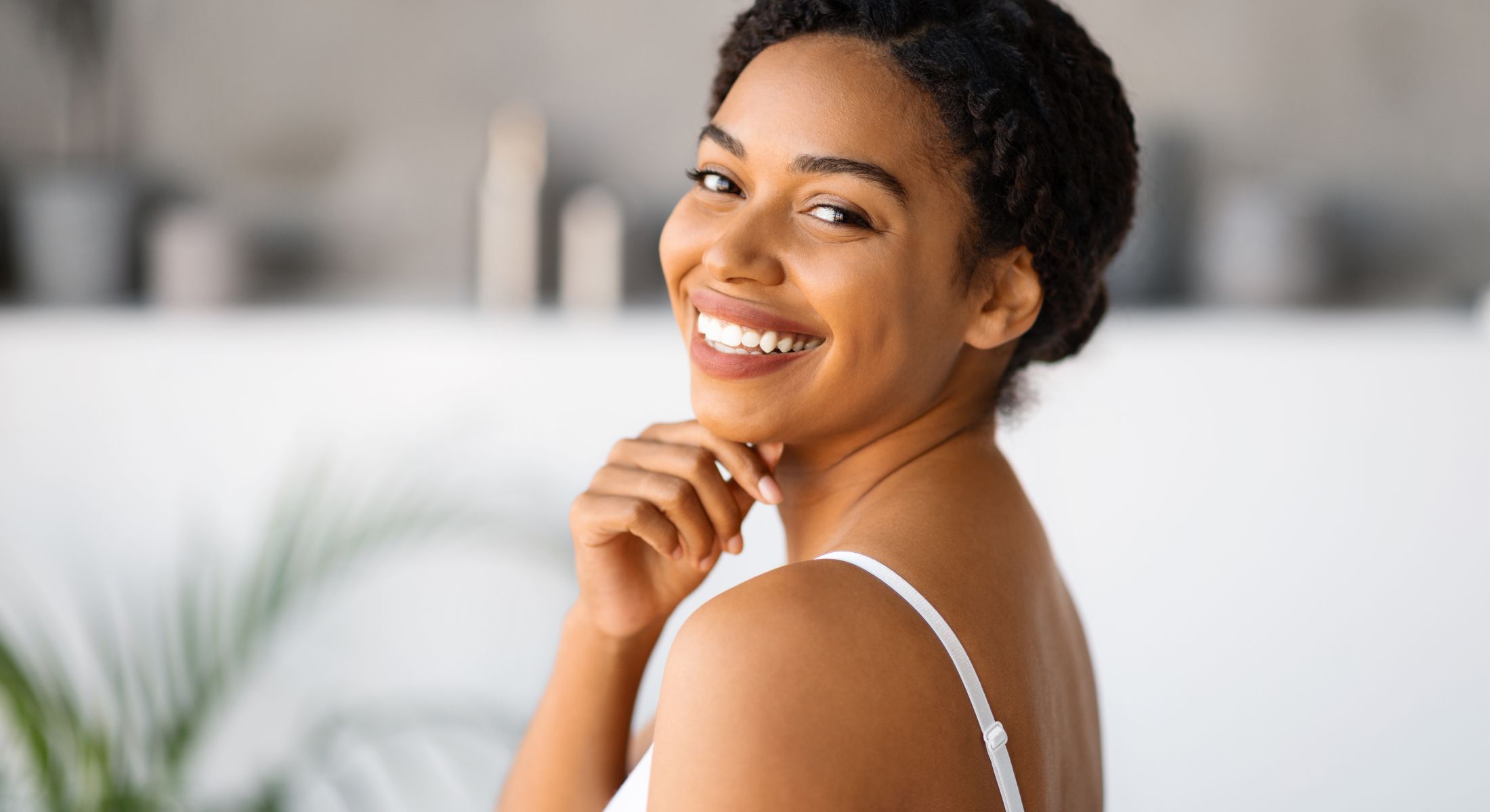 Smiling woman with braided hair, soft background.