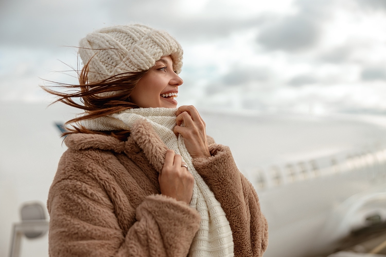 Woman smiling in cozy winter attire outdoors.