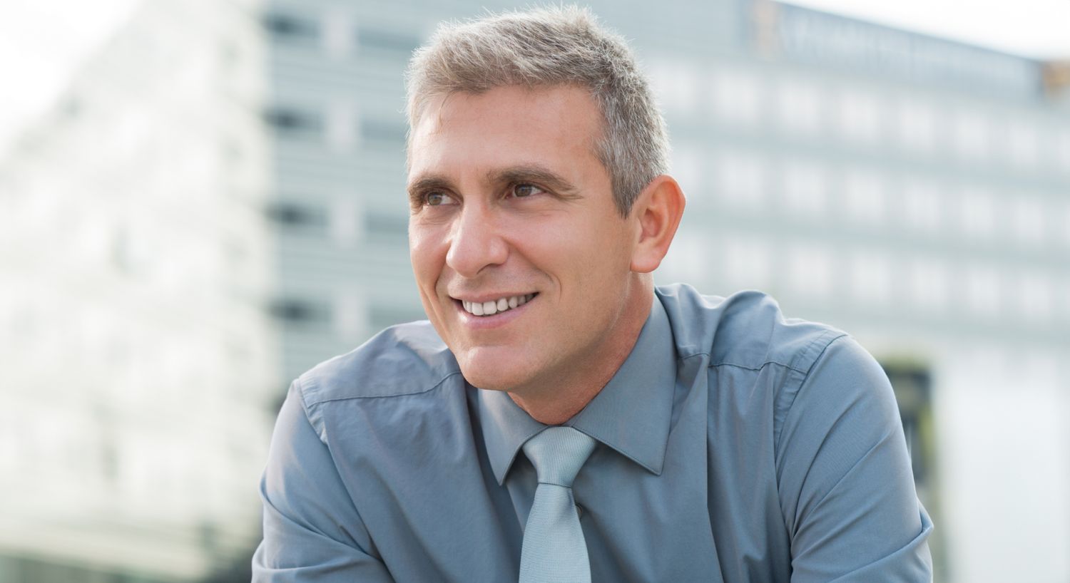 Smiling man in a blue shirt and tie.
