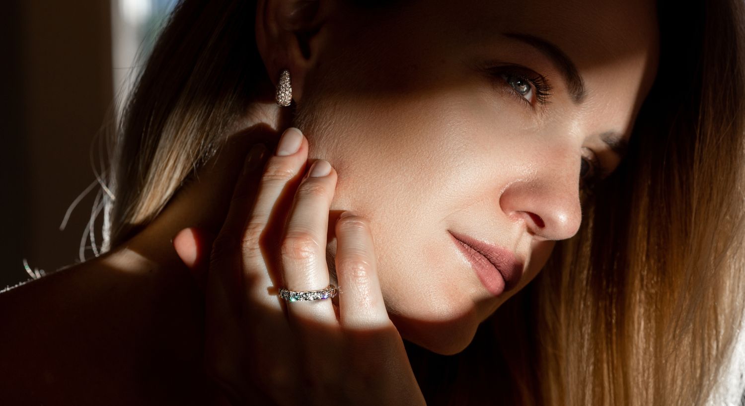 Woman admiring elegant jewelry in soft light.
