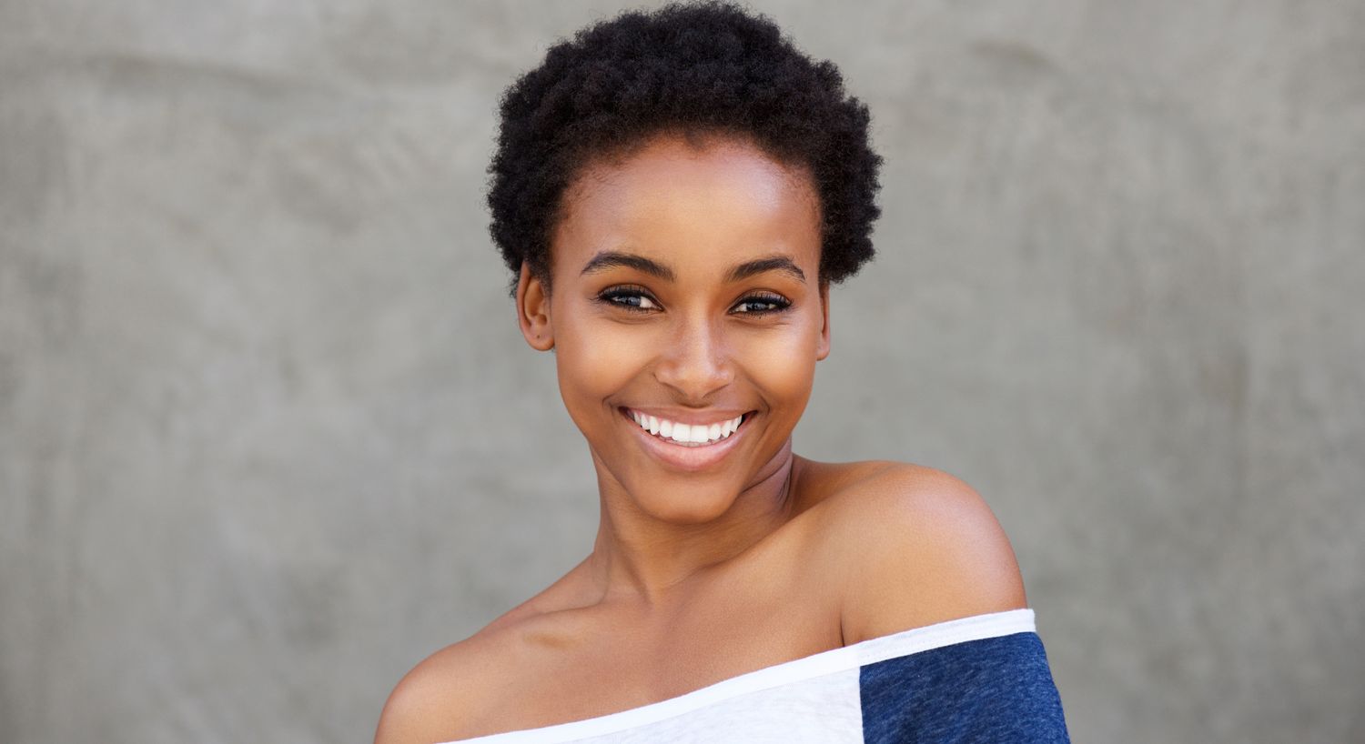 Smiling person with short, curly hair.