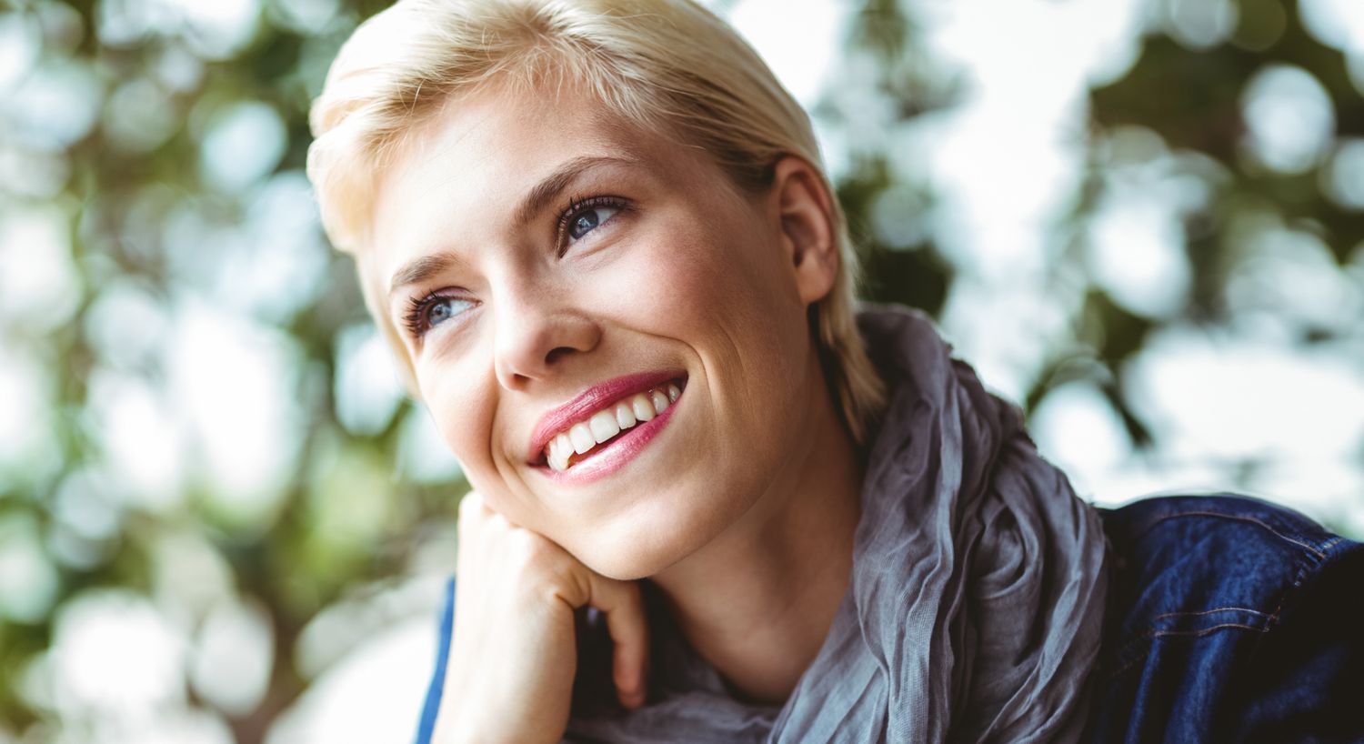 Smiling woman with short blonde hair outdoors.
